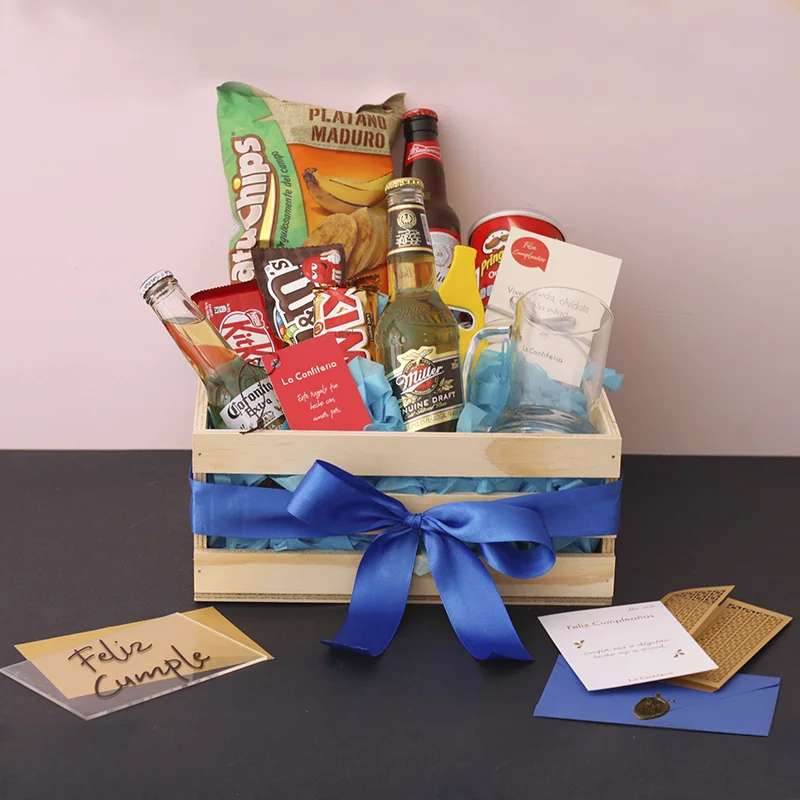 Caja con una cerveza corona y budweiser, papas pringles, twix, M&m, galletas, natuchips y jarra cervecera